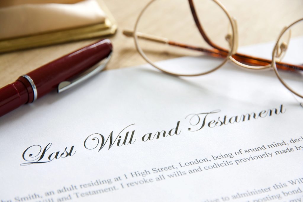 A pen, reading glasses, and a document titled “Last Will and Testament” are placed on a wooden surface—symbolizing the guidance of a Santa Fe Estate Planning Attorney.