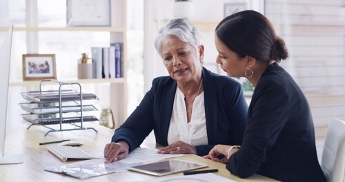 senior female attorney reviewing documents with client at office desk