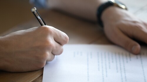 close-up of businessman's hand signing official authorization document with pen